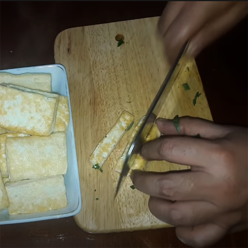 Cắt nhỏ miếng đậu phụ chiên nhằm sẵn sàng nấu nướng canh cà bung lá lốt. (Ảnh dienmayxanh.com)